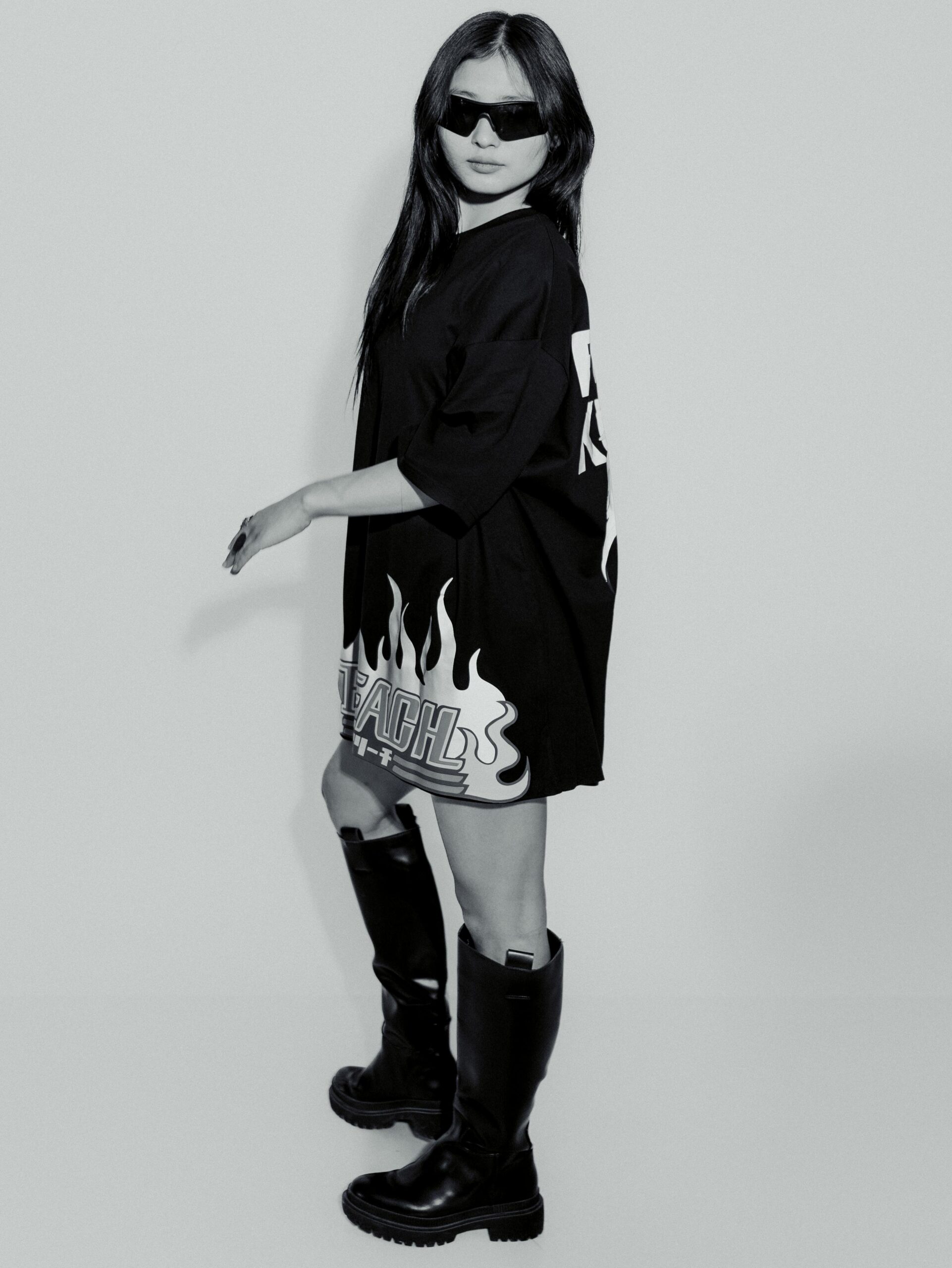 Fashionable woman in black outfit posing with cool sunglasses indoors.