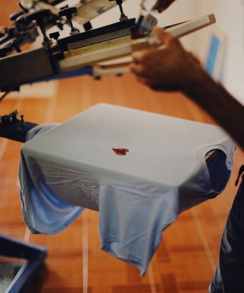 pexels-photo-9314012-9314012 Close-up of a man using a T-shirt printing machine indoors.